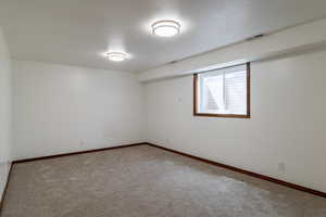 Carpeted spare room with visible vents, baseboards, and a textured ceiling