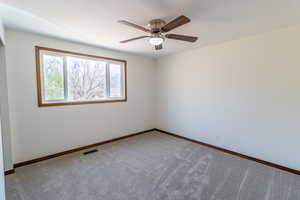 Carpeted empty room featuring visible vents, baseboards, and ceiling fan