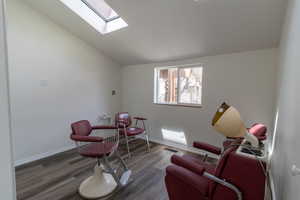 Living area featuring wood finished floors, baseboards, visible vents, and lofted ceiling with skylight