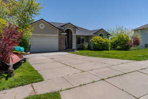 Ranch-style house featuring a garage, stucco siding, concrete driveway, a front lawn, and brick siding