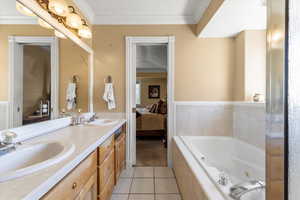 Ensuite bathroom with tile patterned floors, connected bathroom, a whirlpool tub, and a sink