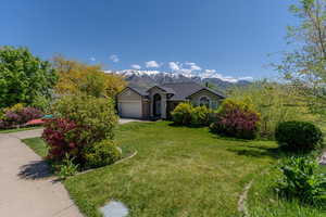 Ranch-style house featuring a front lawn, a mountain view, a garage, and concrete driveway