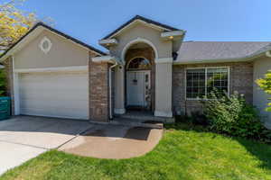 Ranch-style home featuring an attached garage, brick siding, driveway, a front yard, and a shingled roof