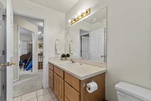 Half bath with toilet, tile patterned floors, and vanity