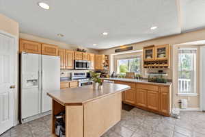Kitchen featuring recessed lighting, white appliances, a sink, open shelves, and a kitchen island