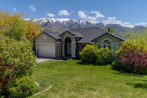 Single story home featuring a mountain view, driveway, a garage, stucco siding, and a front yard