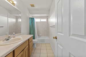 Full bathroom with toilet, vanity, visible vents, tile patterned flooring, and shower / tub combo