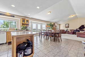 Dining room with light tile patterned floors, a textured ceiling, lofted ceiling, and recessed lighting