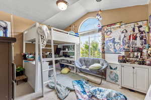 Bedroom with vaulted ceiling and light carpet