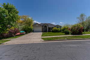 View of front facade featuring concrete driveway, a front yard, and a garage