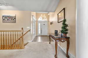 Carpeted entryway with baseboards, a notable chandelier, and tile patterned floors