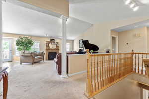 Corridor with light colored carpet, track lighting, and an upstairs landing