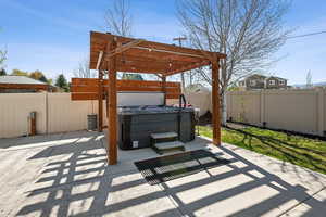 View of patio with a hot tub and a fenced backyard