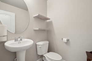 Bathroom with toilet, baseboards, and a sink