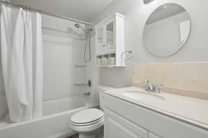 Full bathroom with shower / bath combo with shower curtain, toilet, and vanity