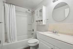Bathroom with shower / bath combo with shower curtain, toilet, and vanity