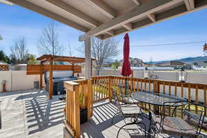 Wooden terrace with a residential view, outdoor dining area, a hot tub, a fenced backyard, and a patio area