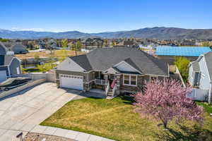 View of front of property featuring stone siding, fence, a garage, and a residential view