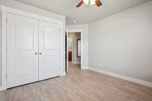 Unfurnished bedroom featuring baseboards, a closet, a ceiling fan, and light wood-style floors