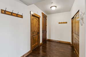 Hall featuring baseboards, dark wood-style floors, and a textured ceiling