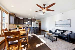 Living room with dark wood-type flooring, recessed lighting, and a ceiling fan
