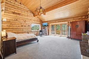 Carpeted bedroom with wood ceiling, high vaulted ceiling, multiple windows, and access to exterior