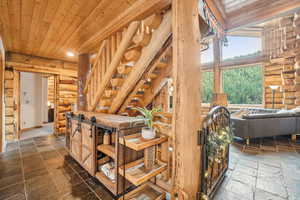 Corridor with stone tile floors, recessed lighting, wood ceiling, and log walls