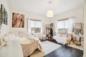 Bedroom with multiple windows and dark wood-type flooring