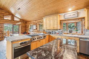 Kitchen with wooden ceiling, log walls, a sink, a peninsula, and appliances with stainless steel finishes