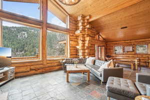 Living area featuring high vaulted ceiling, wood ceiling, and rustic walls