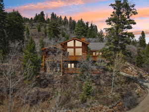 Back of house with a chimney, log exterior, a deck, and a balcony