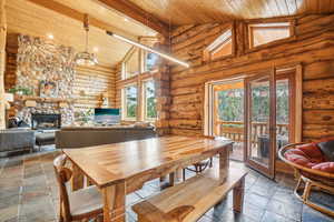 Dining room featuring wood ceiling, log walls, stone tile floors, and high vaulted ceiling