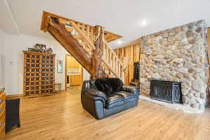 Living room with stairs, wood walls, wood finished floors, recessed lighting, and a fireplace