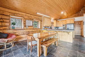 Dining room with wooden ceiling, log walls, lofted ceiling, and stone tile flooring