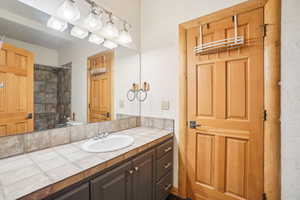 Bathroom with vanity, a textured wall, and bathing tub / shower combination