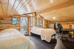 Bedroom featuring lofted ceiling, wood ceiling, rustic walls, and access to exterior