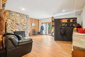 Living room featuring recessed lighting, a stone fireplace, and wood finished floors