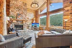 Living room with wood ceiling, high vaulted ceiling, log walls, a stone fireplace, and a chandelier