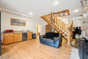 Living room with recessed lighting, beverage cooler, indoor wet bar, stairway, and light wood-type flooring