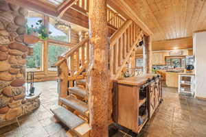 Staircase featuring wooden ceiling, stone tile floors, and rustic walls