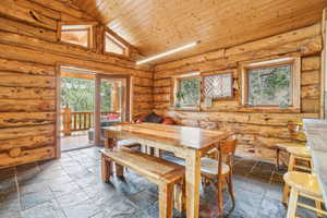 Dining room featuring a wealth of natural light, wood ceiling, high vaulted ceiling, and stone tile flooring