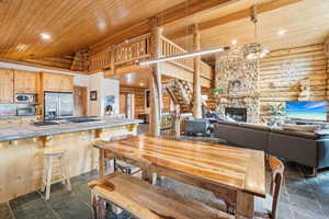 Dining room featuring log walls, stone tile floors, wood ceiling, and high vaulted ceiling