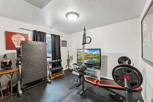 Exercise area with a textured ceiling, visible vents, and baseboards