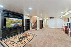 Carpeted living room featuring stairway, baseboards, and recessed lighting