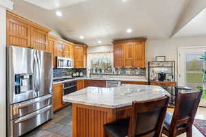 Kitchen with recessed lighting, stone finish flooring, a sink, backsplash, and appliances with stainless steel finishes