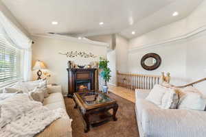 Living room with lofted ceiling, a glass covered fireplace, and recessed lighting