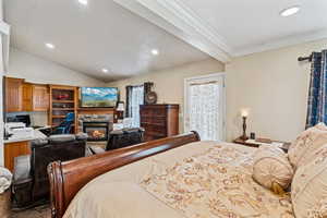 Bedroom featuring a fireplace, lofted ceiling, ornamental molding, and recessed lighting