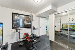 Workout room featuring baseboards and a textured ceiling