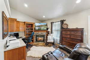 Home office featuring lofted ceiling, a fireplace, and recessed lighting