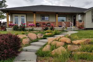 View of front facade featuring a front lawn, a shingled roof, and a porch